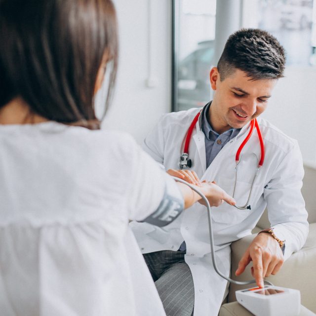 Young male psysician with patient measuring blood pressure